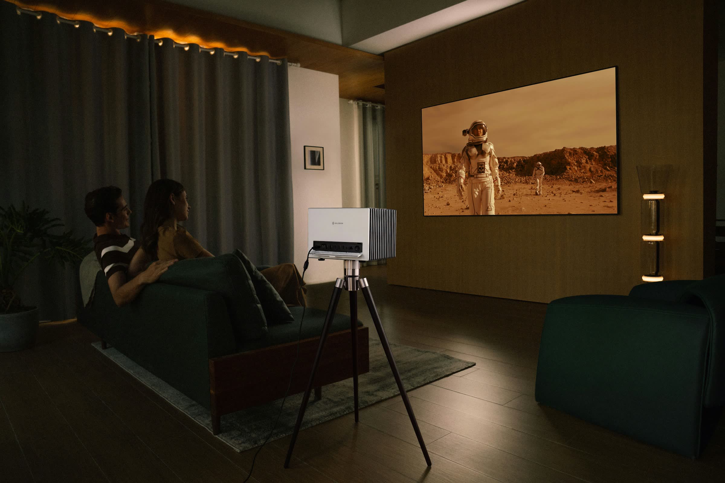 Un couple regarde un film projeté sur grand écran, un soir à la maison
