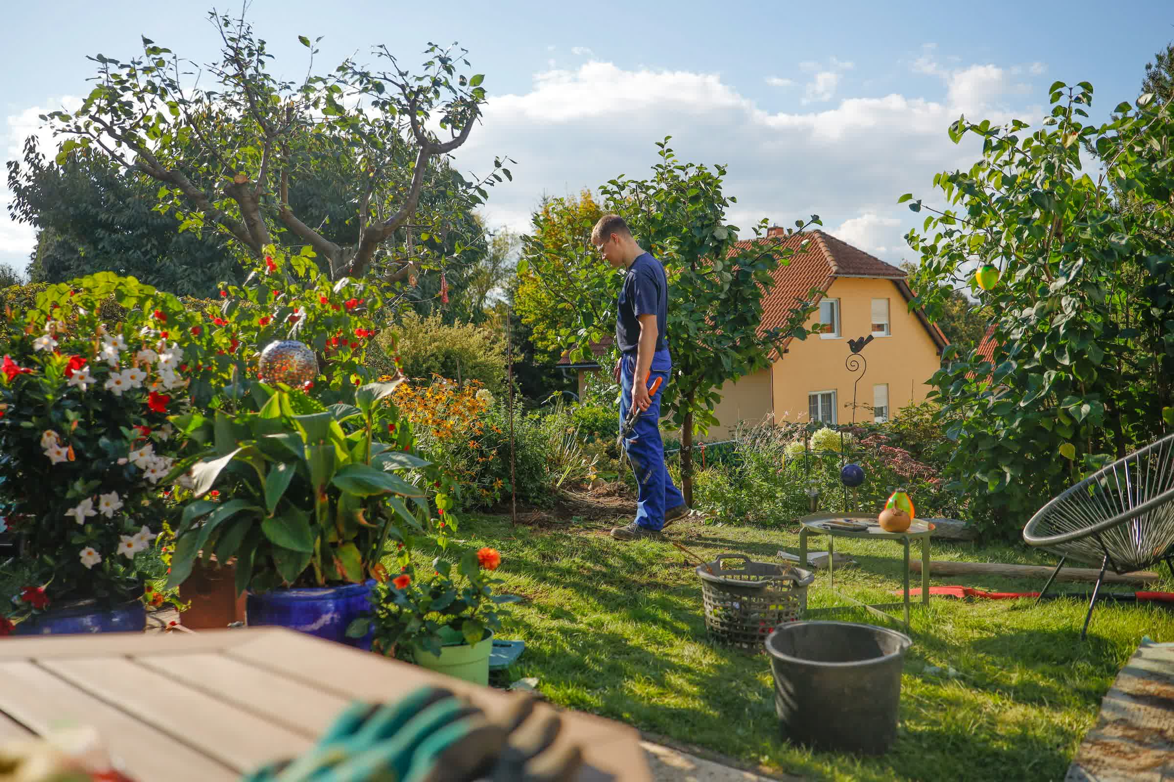 Un homme dans son jardin, sa maison en arrière-plan
