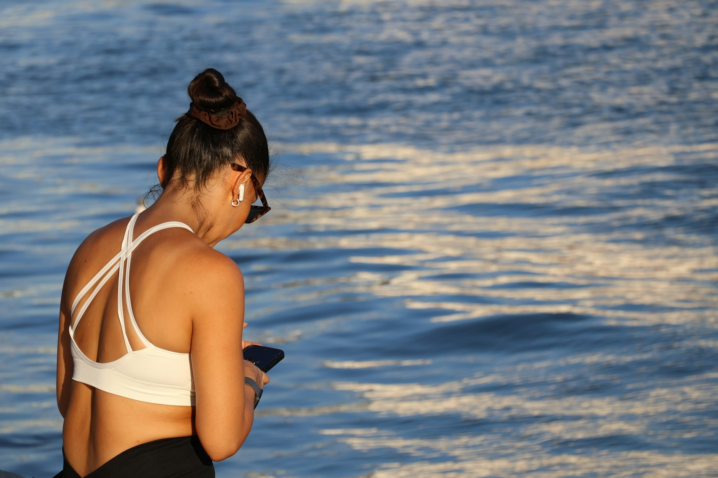 Pause après le sport au bord de l'eau, téléphone à la main