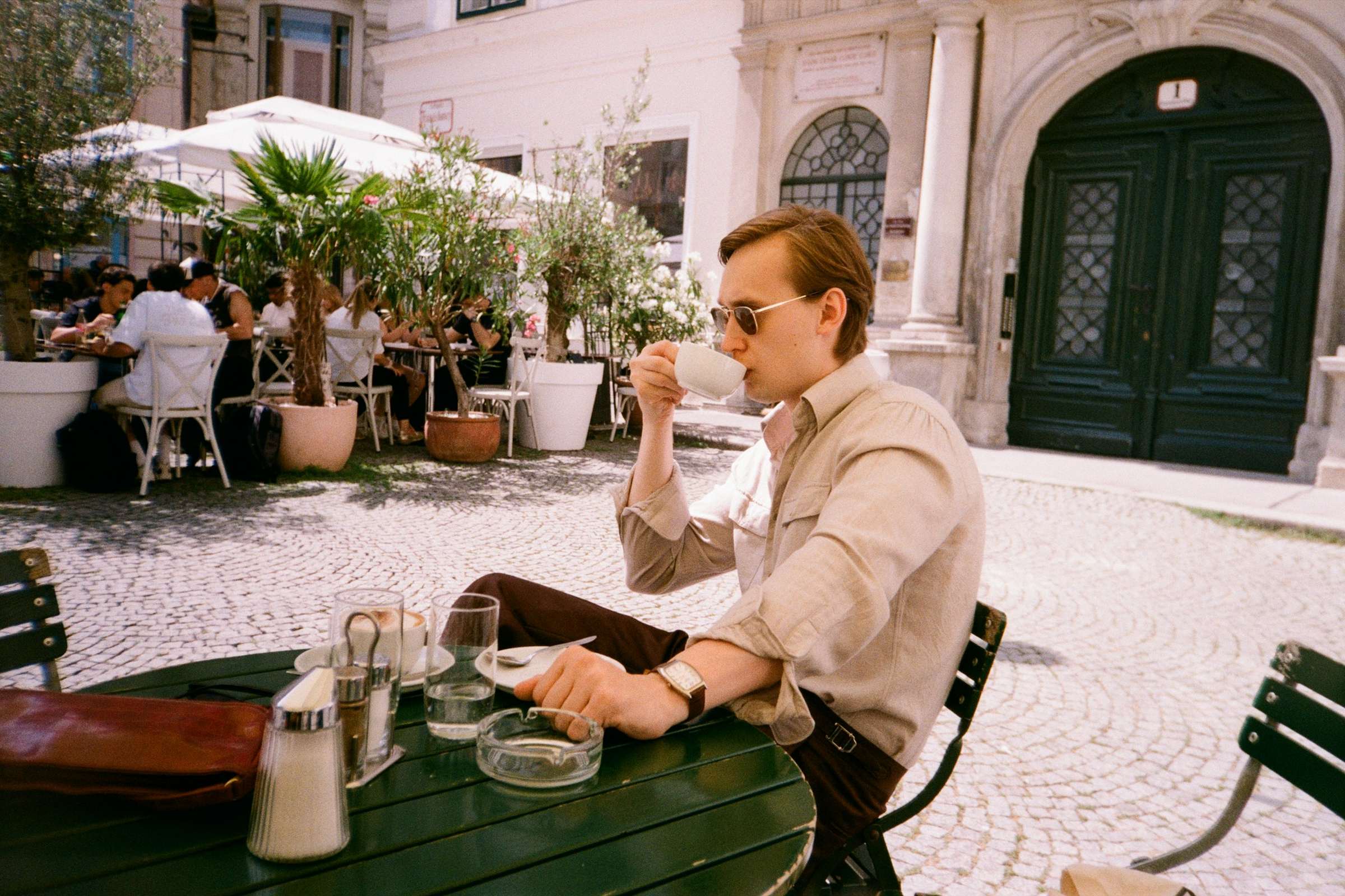 Un homme installé en terrasse, détendu, son téléphone à la main